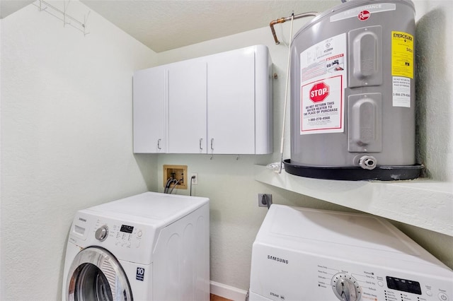 clothes washing area with cabinets, washer and clothes dryer, and electric water heater