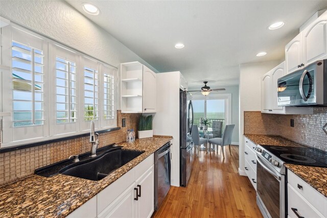 6423 Driftwood Dr, Hudson, FL 34667 - kitchen with appliances with stainless steel finishes, a sink, light wood-style flooring, white cabinets, and decorative backsplash