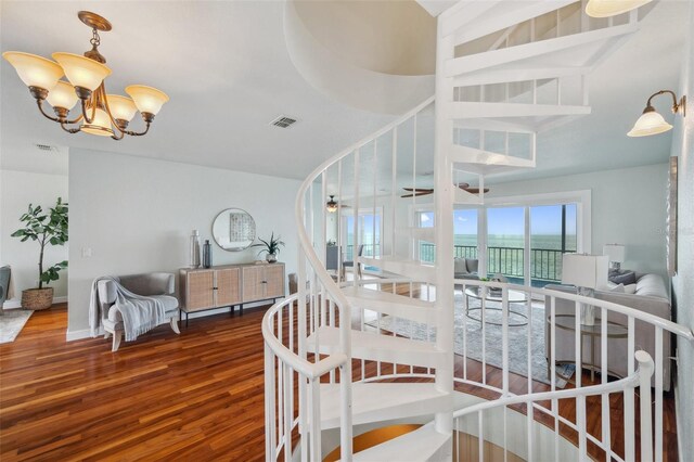 6423 Driftwood Dr, Hudson, FL 34667 - staircase featuring wood finished floors, a chandelier, and a water view