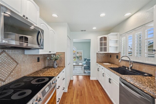 6423 Driftwood Dr, Hudson, FL 34667 - kitchen with stainless steel appliances, a sink, dark stone countertops, light wood-style flooring, and recessed lighting