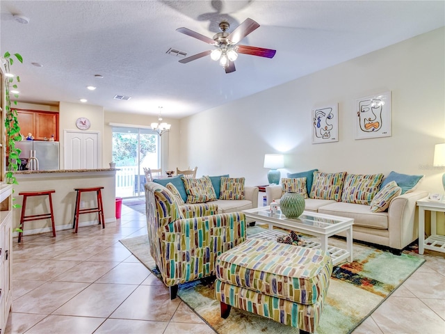 tiled living room with ceiling fan with notable chandelier and a textured ceiling