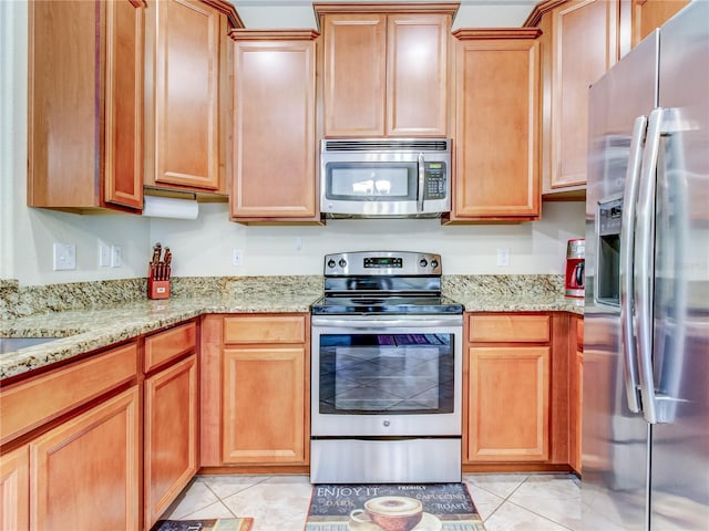 kitchen with light stone countertops, light tile patterned floors, and appliances with stainless steel finishes