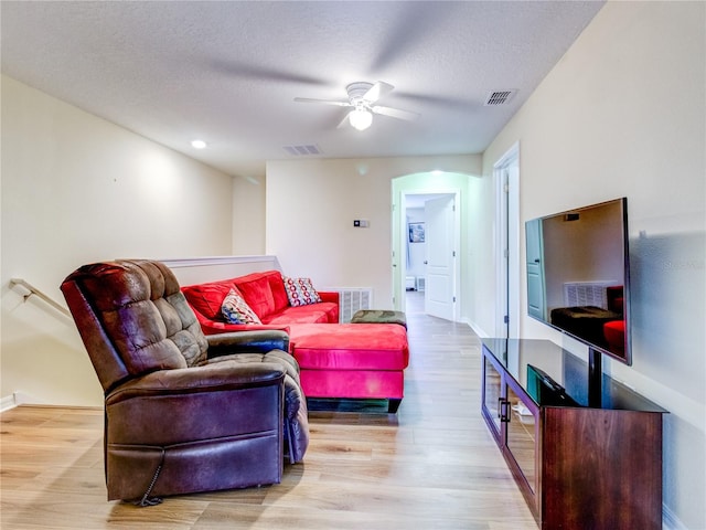 living room featuring ceiling fan, a textured ceiling, and light hardwood / wood-style floors