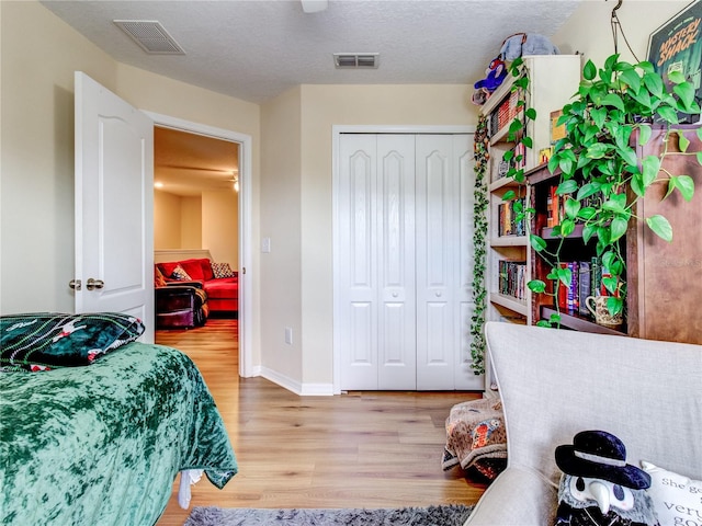 bedroom with light wood-type flooring, a closet, and a textured ceiling