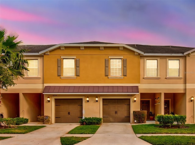 multi unit property featuring a garage, stucco siding, metal roof, and a standing seam roof