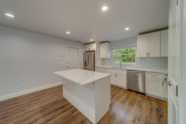 kitchen with a center island, white cabinets, sink, appliances with stainless steel finishes, and tasteful backsplash