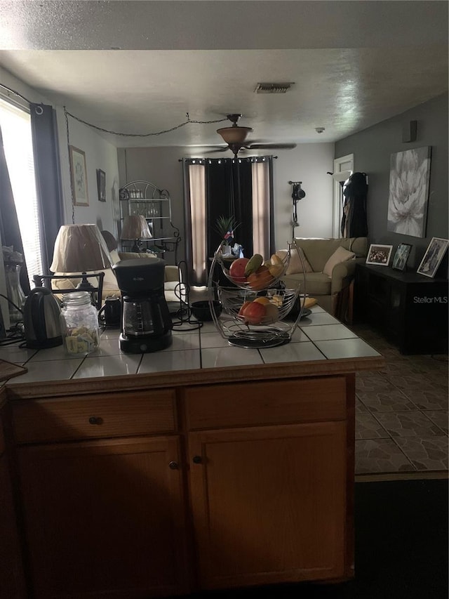 kitchen with ceiling fan and tile counters