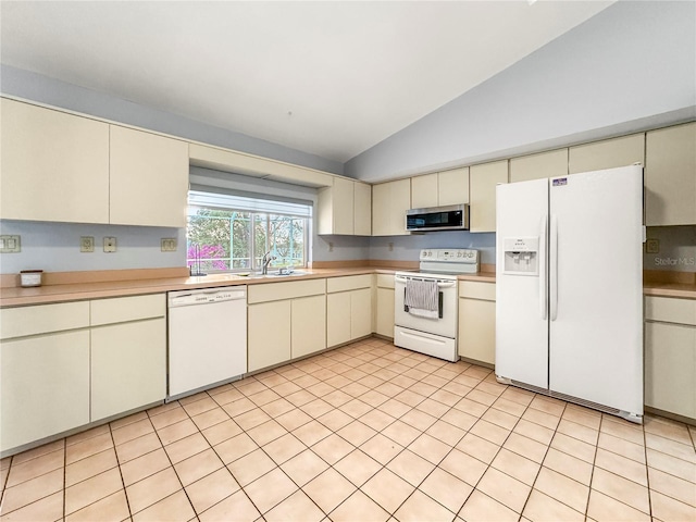 kitchen featuring white appliances, cream cabinets, sink, vaulted ceiling, and light tile patterned floors