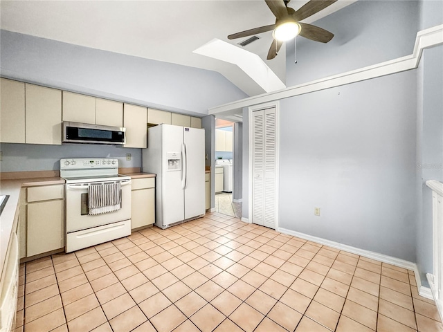 kitchen with lofted ceiling, light tile patterned flooring, white appliances, and cream cabinetry