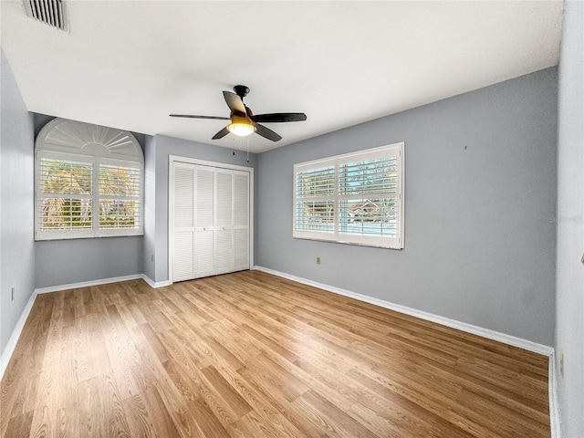 unfurnished bedroom featuring multiple windows, ceiling fan, a closet, and light wood-type flooring