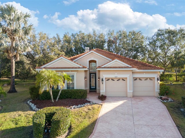 mediterranean / spanish-style house featuring a garage and a front lawn