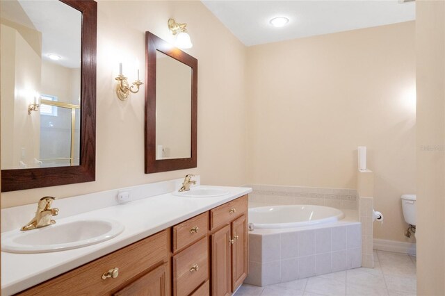 bathroom with toilet, vanity, tile patterned floors, and tiled tub