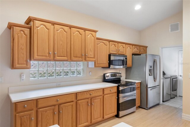 kitchen featuring light hardwood / wood-style floors, stainless steel appliances, and independent washer and dryer