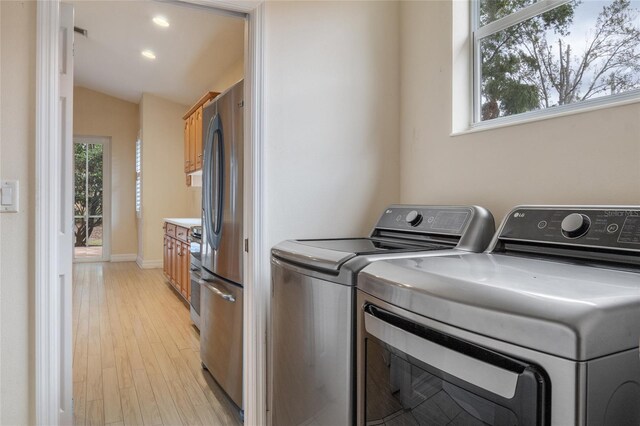 clothes washing area featuring light wood-type flooring and independent washer and dryer