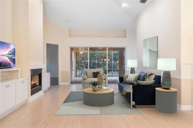 living room featuring high vaulted ceiling, a multi sided fireplace, and light hardwood / wood-style flooring