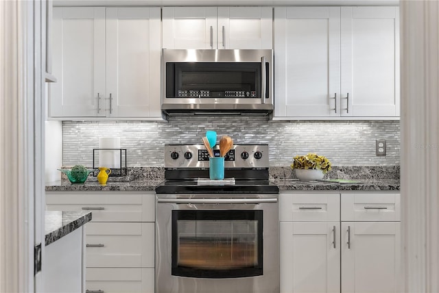 kitchen featuring appliances with stainless steel finishes, white cabinetry, tasteful backsplash, and dark stone counters