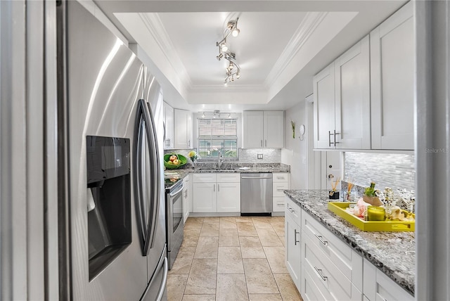 kitchen with stainless steel appliances, decorative backsplash, a raised ceiling, white cabinets, and sink