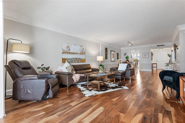 living room with a textured ceiling, crown molding, and wood-type flooring