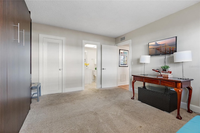 office featuring light carpet, a textured ceiling, and washer / dryer