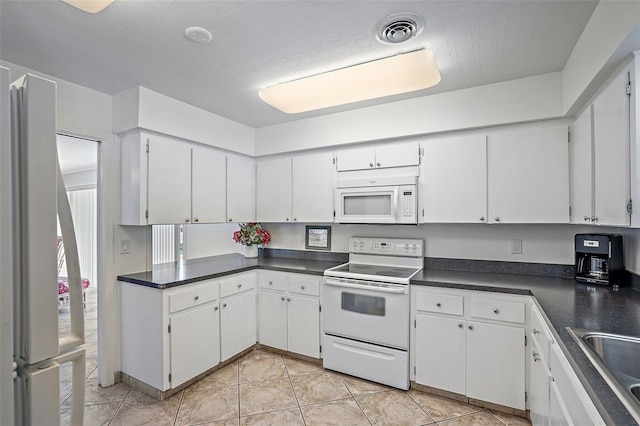 kitchen featuring white appliances, white cabinets, a textured ceiling, sink, and light tile patterned floors