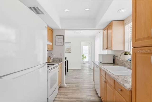 kitchen with white appliances, light brown cabinets, light hardwood / wood-style floors, sink, and light stone counters