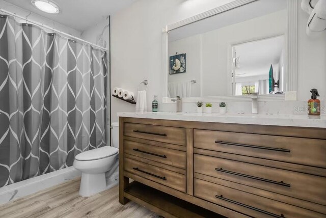 bathroom featuring hardwood / wood-style flooring, toilet, vanity, and a shower with curtain