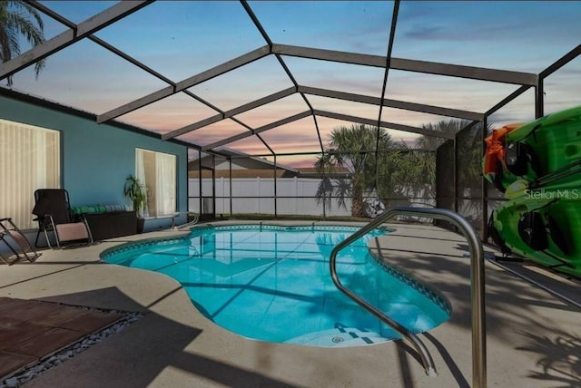 pool at dusk featuring a patio area and glass enclosure