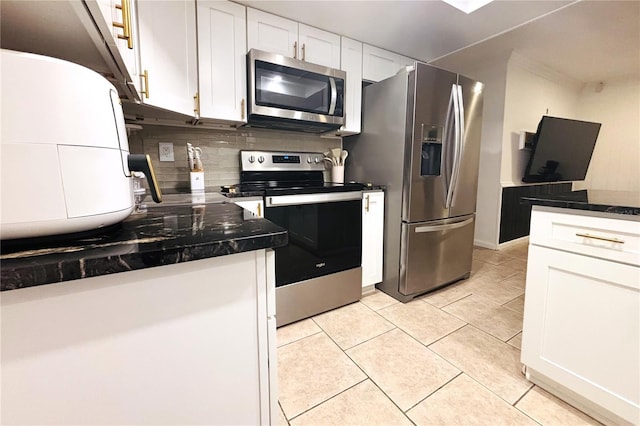 kitchen featuring white cabinets, decorative backsplash, dark stone countertops, light tile patterned floors, and stainless steel appliances