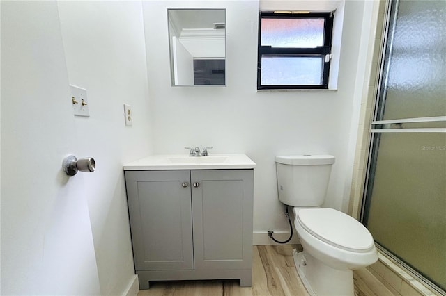 bathroom with hardwood / wood-style floors, vanity, toilet, and an enclosed shower