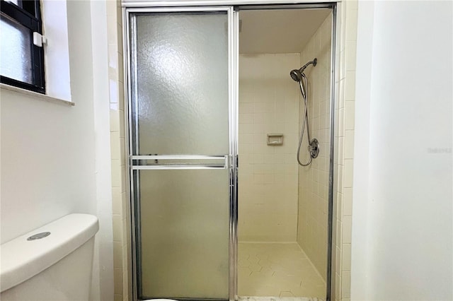 bathroom with a shower with shower door and toilet