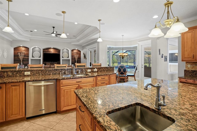 kitchen with dishwasher, dark stone countertops, hanging light fixtures, a tray ceiling, and sink