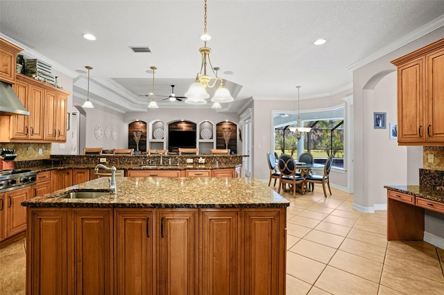 kitchen with sink, decorative backsplash, dark stone counters, pendant lighting, and crown molding