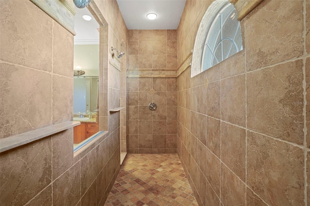 bathroom with ornamental molding, a tile shower, and vanity