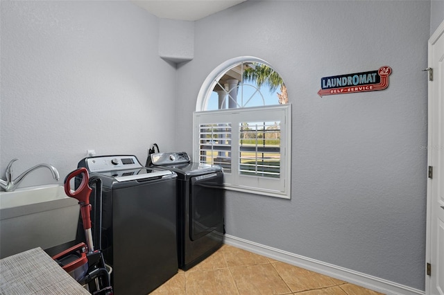 clothes washing area featuring independent washer and dryer, light tile patterned floors, and sink