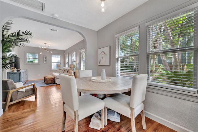 dining space with hardwood / wood-style flooring and a notable chandelier