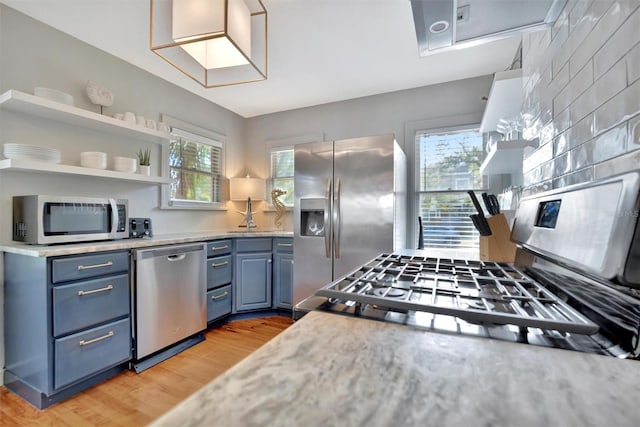 kitchen featuring sink, blue cabinets, light hardwood / wood-style floors, and appliances with stainless steel finishes