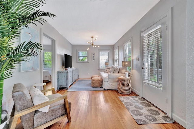 living room with a wealth of natural light, light hardwood / wood-style floors, and an inviting chandelier