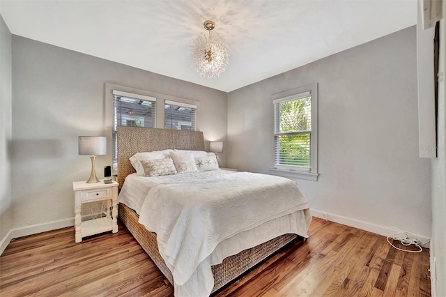 bedroom with light hardwood / wood-style floors and a notable chandelier