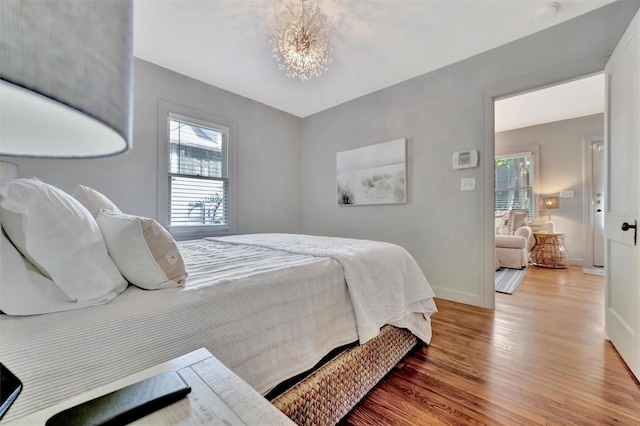 bedroom with hardwood / wood-style flooring and an inviting chandelier