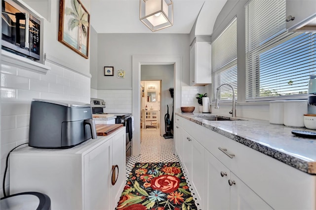 kitchen featuring white cabinets, sink, light stone countertops, and stainless steel appliances