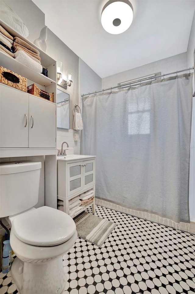 bathroom featuring walk in shower, vanity, and toilet