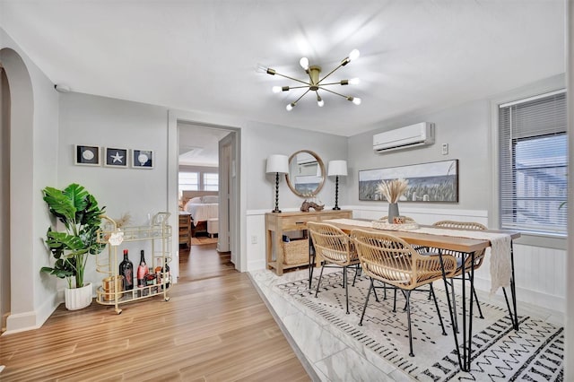 dining area featuring wood-type flooring, an inviting chandelier, and a wall mounted AC