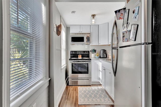 kitchen featuring light hardwood / wood-style floors, white cabinetry, a healthy amount of sunlight, and appliances with stainless steel finishes