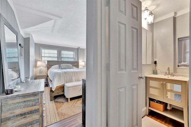 bedroom featuring a textured ceiling, light wood-type flooring, and sink