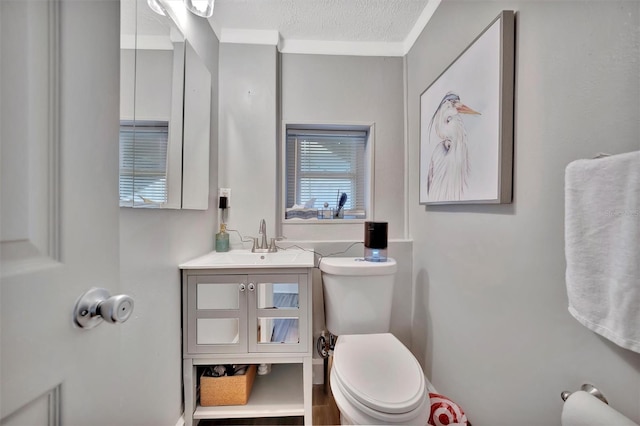 bathroom with a textured ceiling, vanity, toilet, and crown molding