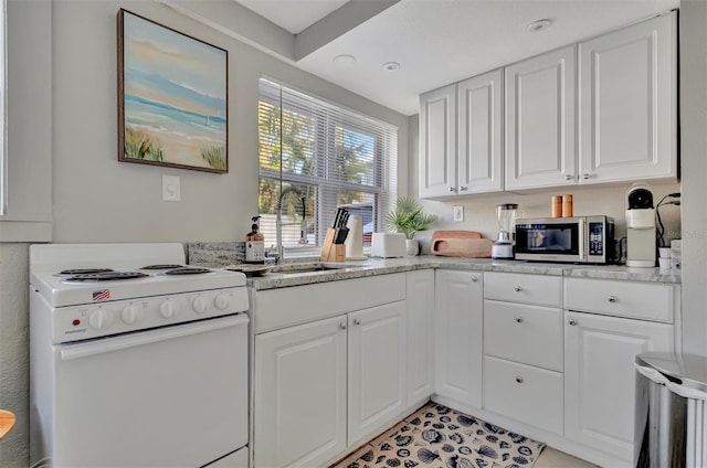 kitchen featuring white cabinetry, sink, light stone counters, and white stove