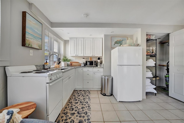 kitchen featuring sink, white appliances, white cabinetry, and light tile patterned flooring