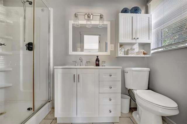 bathroom featuring tile patterned floors, a shower with door, vanity, and toilet