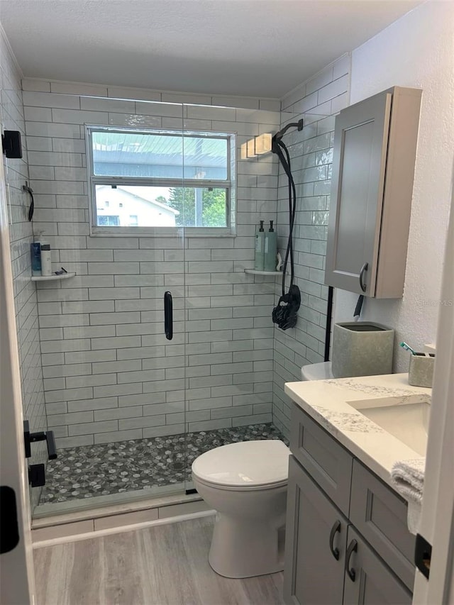 bathroom with toilet, vanity, walk in shower, and hardwood / wood-style flooring