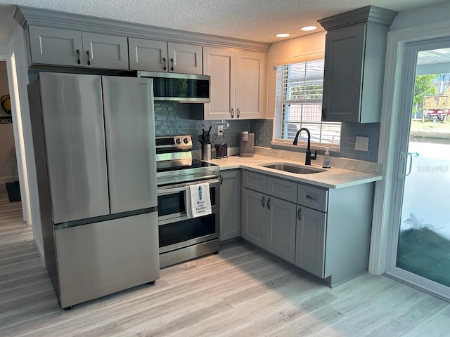 kitchen featuring appliances with stainless steel finishes, gray cabinetry, light hardwood / wood-style floors, and sink